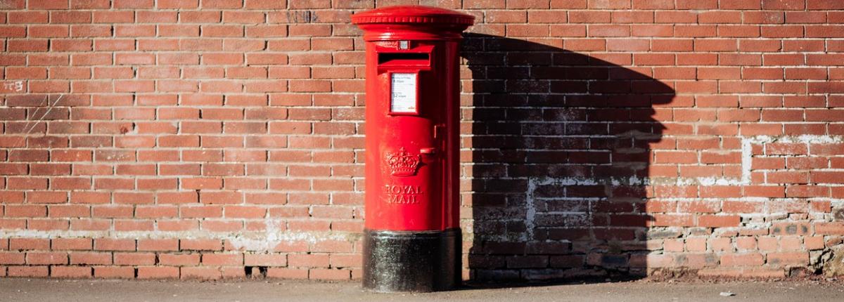 Red post box set against a brick wall
